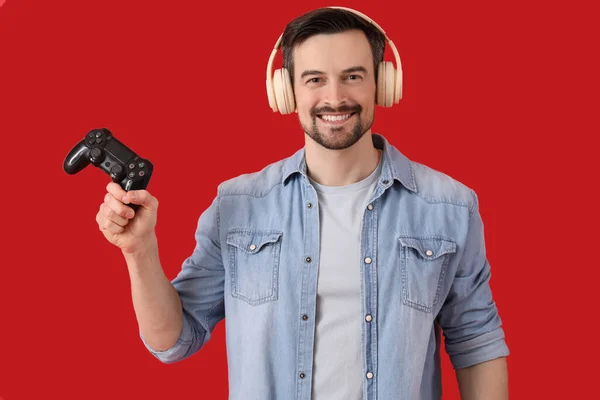 Schöner Mann Mit Kopfhörer Und Spielkissen Auf Rotem Hintergrund — Stockfoto