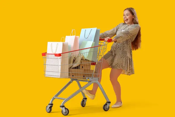 Gelukkig Vrouwelijke Verkoper Met Boodschappentassen Winkelwagentje Gele Achtergrond — Stockfoto