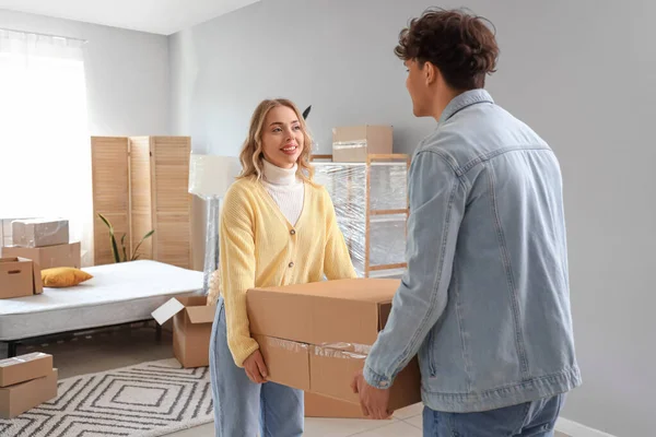 Young couple carrying box in bedroom on moving day