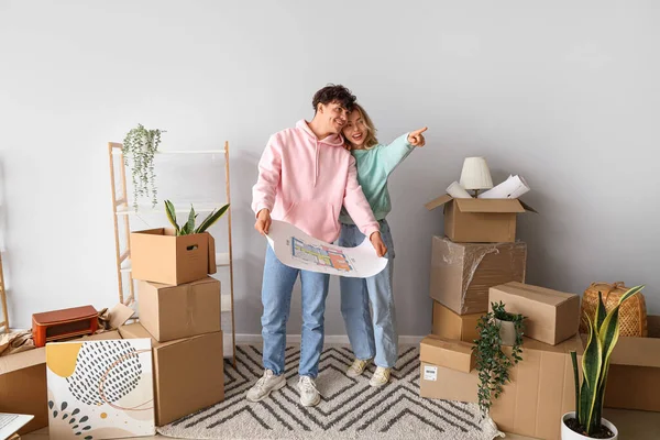 Happy young couple with house plan in room on moving day