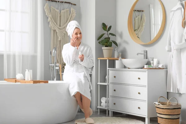 stock image Mature woman applying essential oil in bathroom