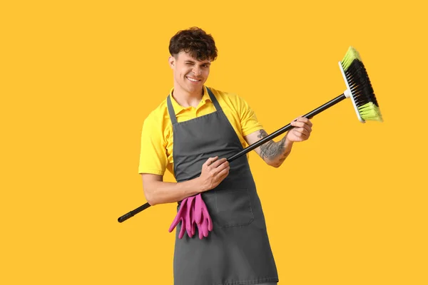 Männlicher Hausmeister Spielt Mit Besen Auf Gelbem Hintergrund — Stockfoto