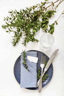 Beyaz arka planda katlanmış peçete, boş kart ve çatal bıçak takımı.