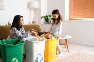 Asyalı bir anne ve küçük kızı evde çöp kutularını düzenliyorlar.