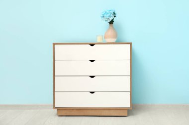 Şık beyaz çekmeceli şakayık çiçekli ve mavi duvarlı bir çekmece.