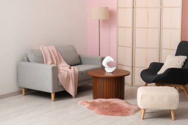 Koltuklar ahşap sehpa, puf ve tuvalet perdesi pembe duvarın yanında.