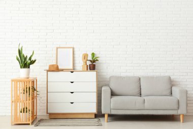 Çekmeceleri, kanepesi ve rafları olan aydınlık oturma odasının içinde.