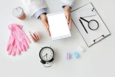 Doktor beyaz masada tablet bilgisayarla çalışıyor