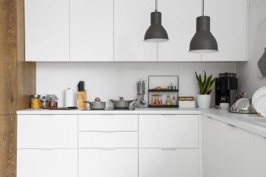 Beyaz mutfak tezgahları elektrikli ocak, tencere ve çatal bıçak.