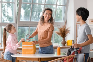 Anne ve küçük çocukları mutfakta öğle yemeği hazırlıyorlar.