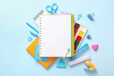 Mavi zemin üzerinde boş defter ve farklı okul sayfası olan kompozisyon