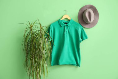 Yeşil arka planda asılı şık tişört ve şapka