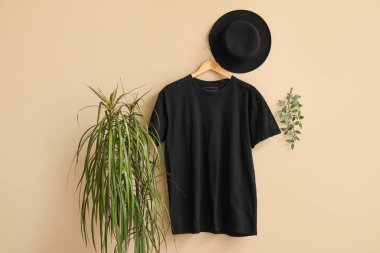 Bej arka planda asılı şık siyah tişört ve şapka