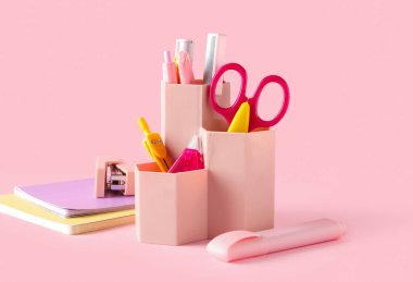 Pembe arka planda farklı kırtasiye malzemesi olan tutucu