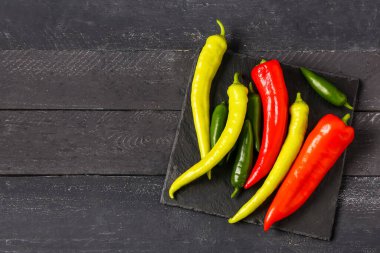 Siyah ahşap arka planda farklı taze kırmızı biberli tahta.