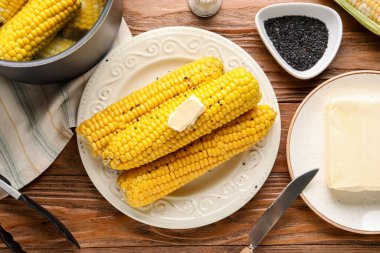 Ahşap arka planda tereyağlı haşlanmış mısır koçanı tabağı.