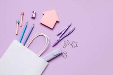 Kağıt torba ile kompozisyon ve leylak arkaplan üzerinde farklı kırtasiye