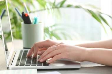 Ofisteki masada modern laptop kullanan bir kadın.