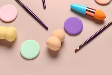 Bej arka planda makyaj süngerleri ve fırçalar