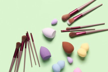 Yeşil arkaplanda makyaj süngerleri ve fırçalar
