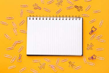 Turuncu arkaplanda not defteri ve ataç