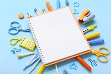 Mavi arkaplanda farklı kırtasiye malzemesi olan defter