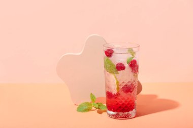 Pembe arka planda bir bardak taze ahududu mojito.