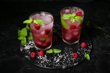 Siyah arka planda taze ahududu mojito bardakları olan tahta.