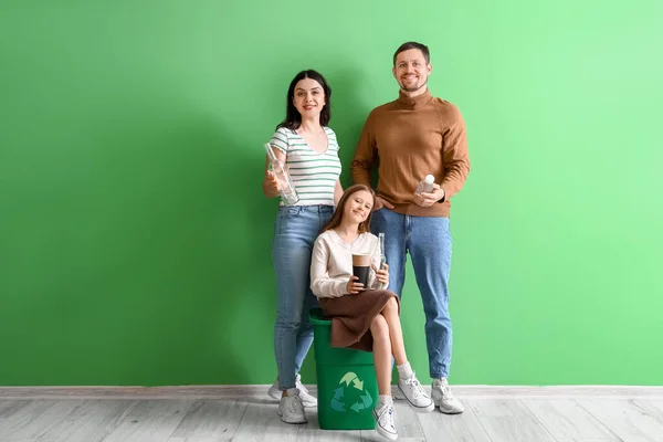 Family with recycle bin near green wall