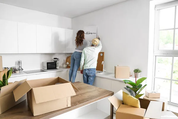 Young couple with poster in kitchen on moving day