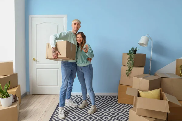Young couple with keys from their new flat and box in room on moving day