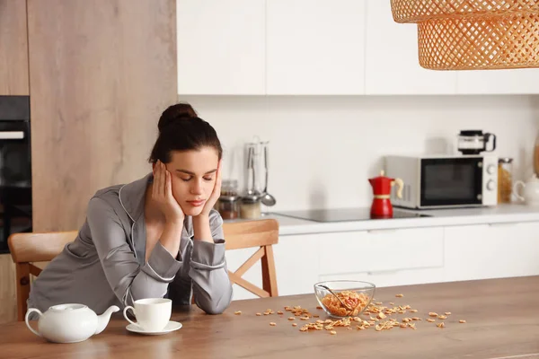 Genç bir kadın mutfakta kahvaltıda uyuyor.