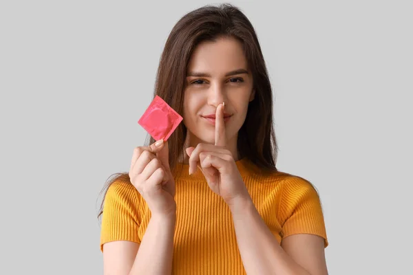 Junge Frau Mit Kondom Zeigt Schweigegegeste Auf Hellem Hintergrund Nahaufnahme — Stockfoto