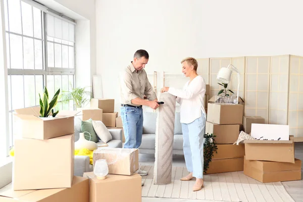 Olgun çift taşınma gününde odada halı topluyor.