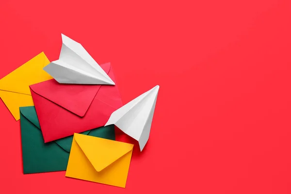 赤い背景に異なる封筒と紙飛行機のセット — ストック写真