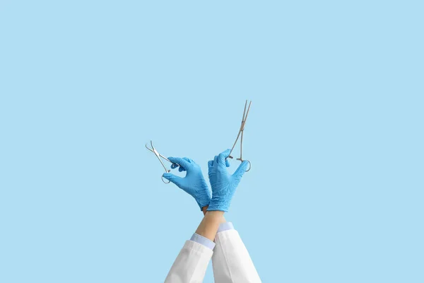 Dłonie Lekarza Kleszczami Chirurgicznymi Niebieskim Tle — Zdjęcie stockowe