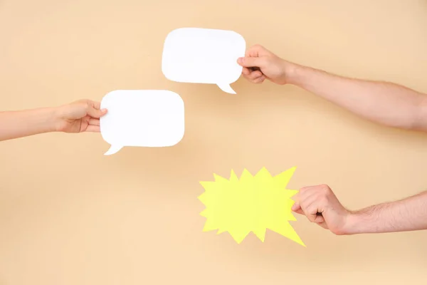 Different hands with speech bubbles on beige background