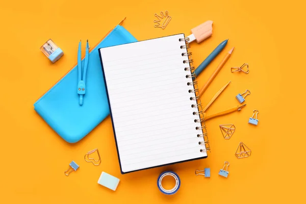 オレンジ色の背景に異なる文房具を備えたノートブックと鉛筆ケース — ストック写真