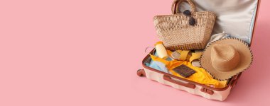 Elbiseli bavul, plaj aksesuarları ve pembe arka planda mesaj için yeri olan pasaport.