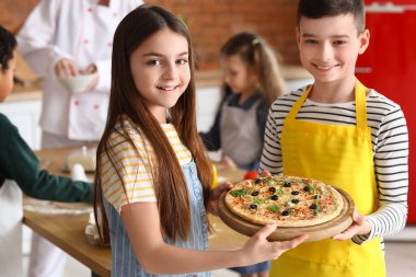 Mutfakta aşçılık kursundan sonra pizza hazırlayan küçük çocuklar.