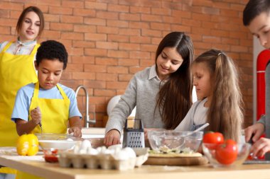 Küçük çocuklar mutfakta yemek kursunda pizza hazırlıyorlar.