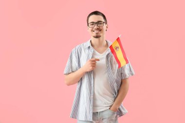 Pembe arka planda İspanya bayrağı taşıyan yakışıklı genç adam.
