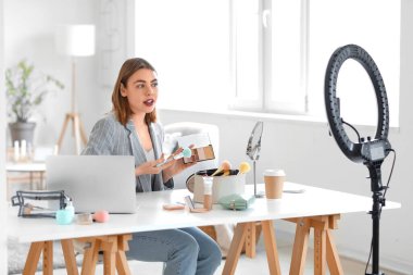 Female beauty blogger with eyeshadows recording video at home