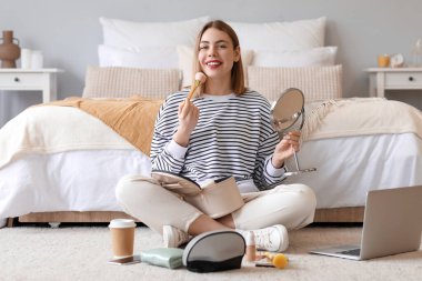 Yatak odasında ayna ve fırçayla oturan genç bir kadın.