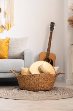Kanepe, hasır sepet ve gitarla aydınlık oturma odasının içinde.