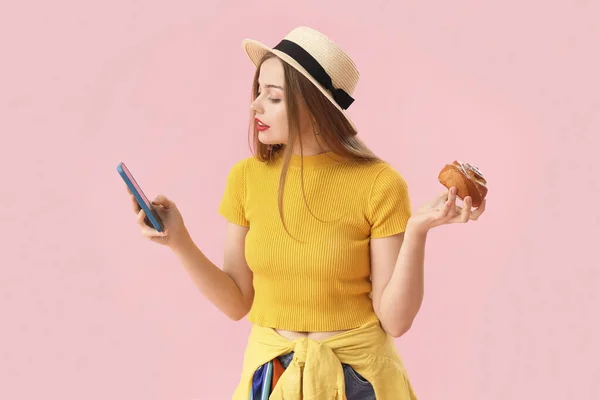 Молодая Женщина Шляпе Вкусной Булочкой Помощью Мобильного Телефона Розовом Фоне — стоковое фото