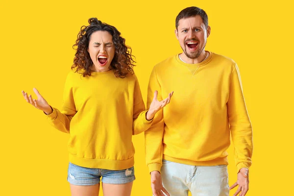 Angry young couple on yellow background