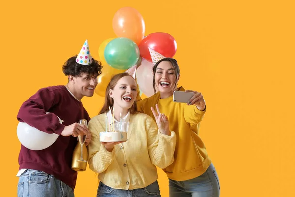 Młodzi Przyjaciele Tortem Urodzinowym Robiący Selfie Żółtym Tle — Zdjęcie stockowe