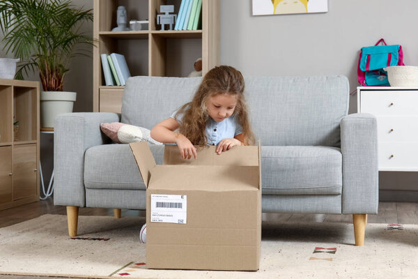 Милая маленькая девочка распаковывает посылку дома
