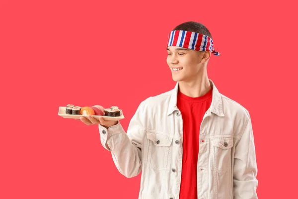 赤い背景でおいしい寿司を持つ若い男 — ストック写真